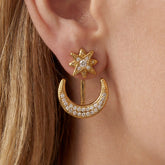 Close up of blonde woman wearing gold star and moon ear jackets celestial jewelry.