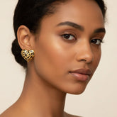 A beautiful side profile of a model with glowing, deep skin wearing The Artemis Earrings, highlighting their bold scale and fierce leopard print.