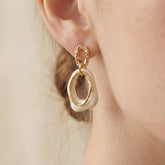 Close up of woman wearing vintage style cream and gold link earrings.