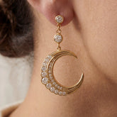 Close up of gold crescent moon earring with pave crystals on model ear celestial jewelry.