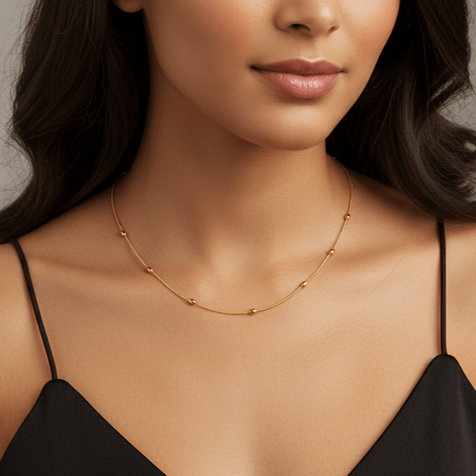 Close-up of a woman's neck wearing the Dainty Beaded Necklace solo with a black sweater, showcasing its delicate look.