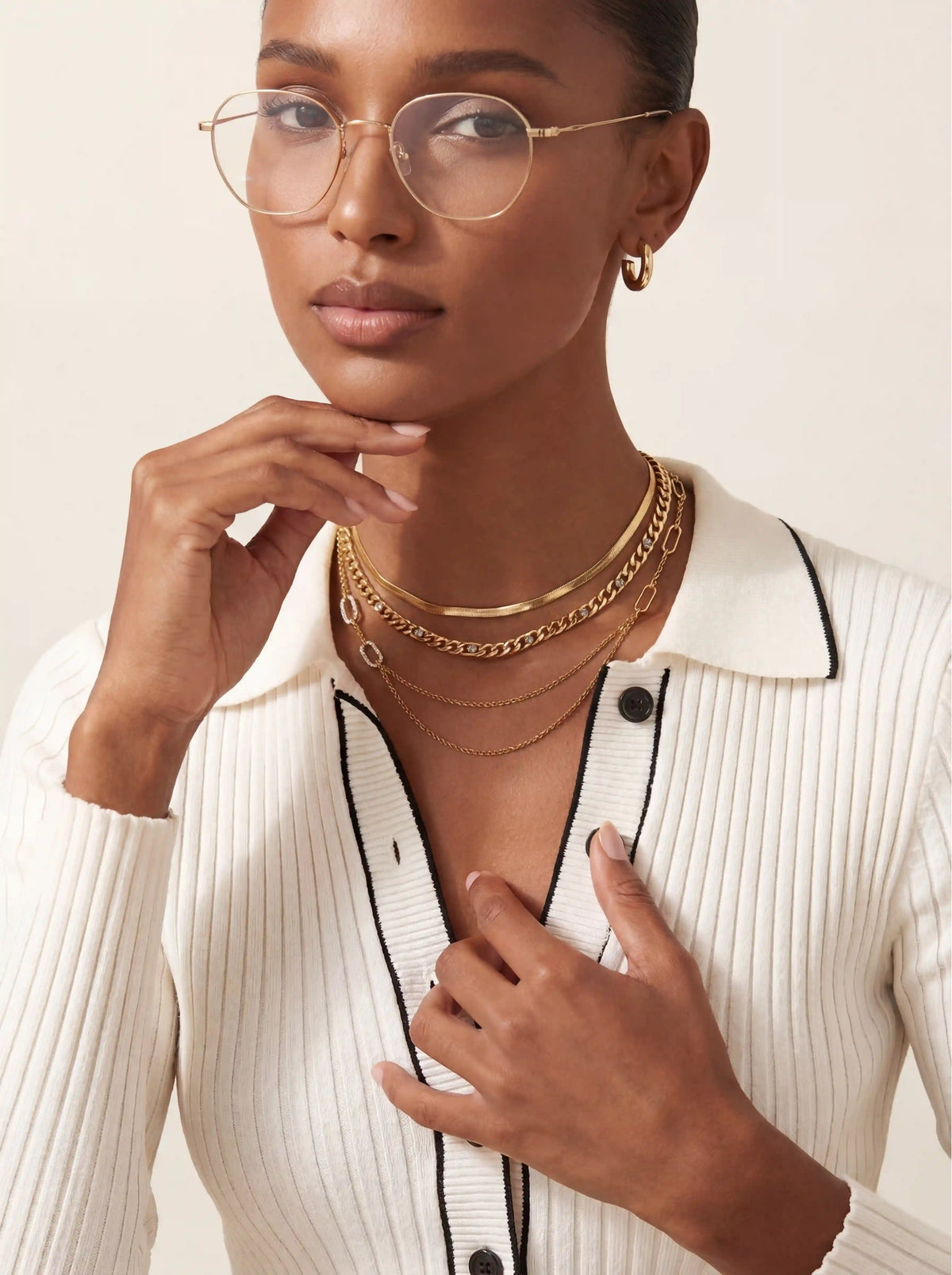 Confident woman with glasses styling gold Daphne draped necklace business casual jewelry.