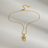 A detailed studio shot of The Evangeline Necklace by Luminova, showcasing the delicate gold guardian angel pendant holding a sparkling crystal, on a clean white background.