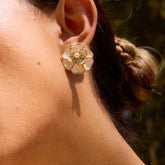 A beautiful close-up of a model in a garden setting, wearing The Fleur Studs which add a touch of timeless elegance to her look.