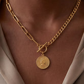 Close up of mixed chain coin necklace with front toggle clasp on model wearing beige top.