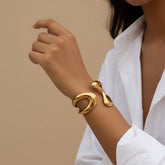 A close-up of a model's wrist, wearing The Pythia Cuff over a classic white shirt sleeve, demonstrating its power as a statement accessory.