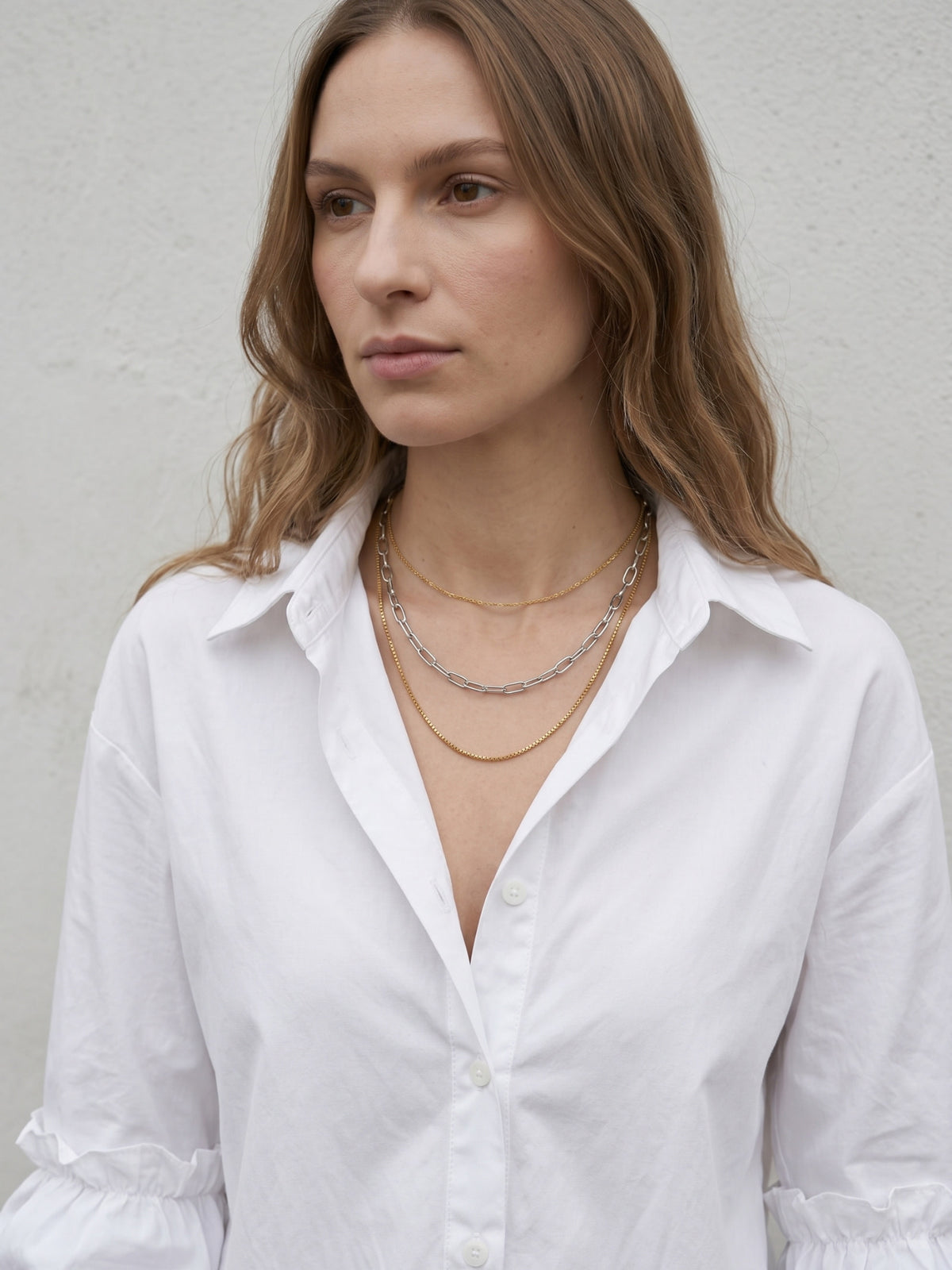 Two-tone layered chain necklace styled with minimalist white shirt