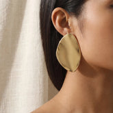 Woman wearing large gold organic shape stud earrings vintage 80s style.