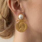 Close up of gold coin earring with pearl stud vintage baroque style jewelry on woman.