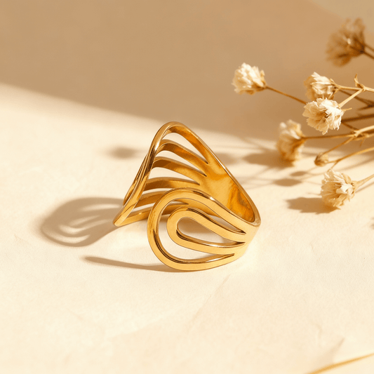 The Liquid Gold Ring in 18k gold plate on a beige background. The image details its abstract swirl design and open cuff, with annotations for its dimensions (1.87cm width), weight (3.7g), and materials (Waterproof, Hypoallergenic Stainless Steel).