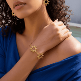 Radiant Sun Charm Bracelet worn on a female wrist, showcasing the boho jewelry stack with other gold bracelets.