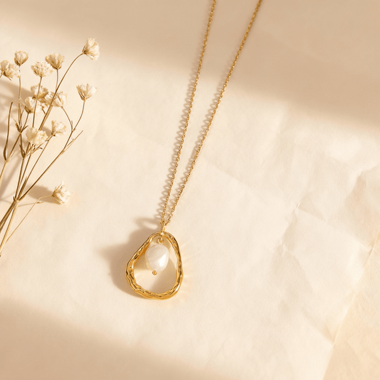 A detailed close-up of The Luna Pearl necklace, focusing on the sleek, polished bail that securely holds the freshwater pearl and connects it to the delicate, woven-style titanium steel chain. The image highlights the high-quality construction.