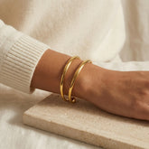 Minimalist jewelry styling gold geometric open cuff on woman wrist.