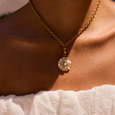 A beautiful close-up of The Fleur Pendant on a model's collarbone, highlighting the intricate details of the white camellia and its central pearl.