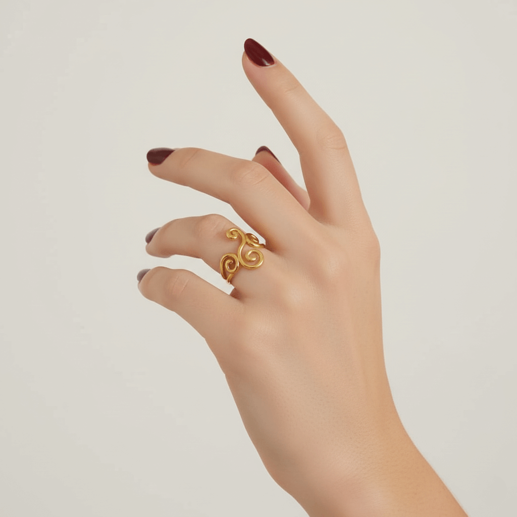 A model's delicate hand, with a soft, natural manicure, wearing The Aphrodite Ring on her middle finger. The ring's open, airy vine design wraps beautifully across her knuckle, creating an elegant, statement look.
