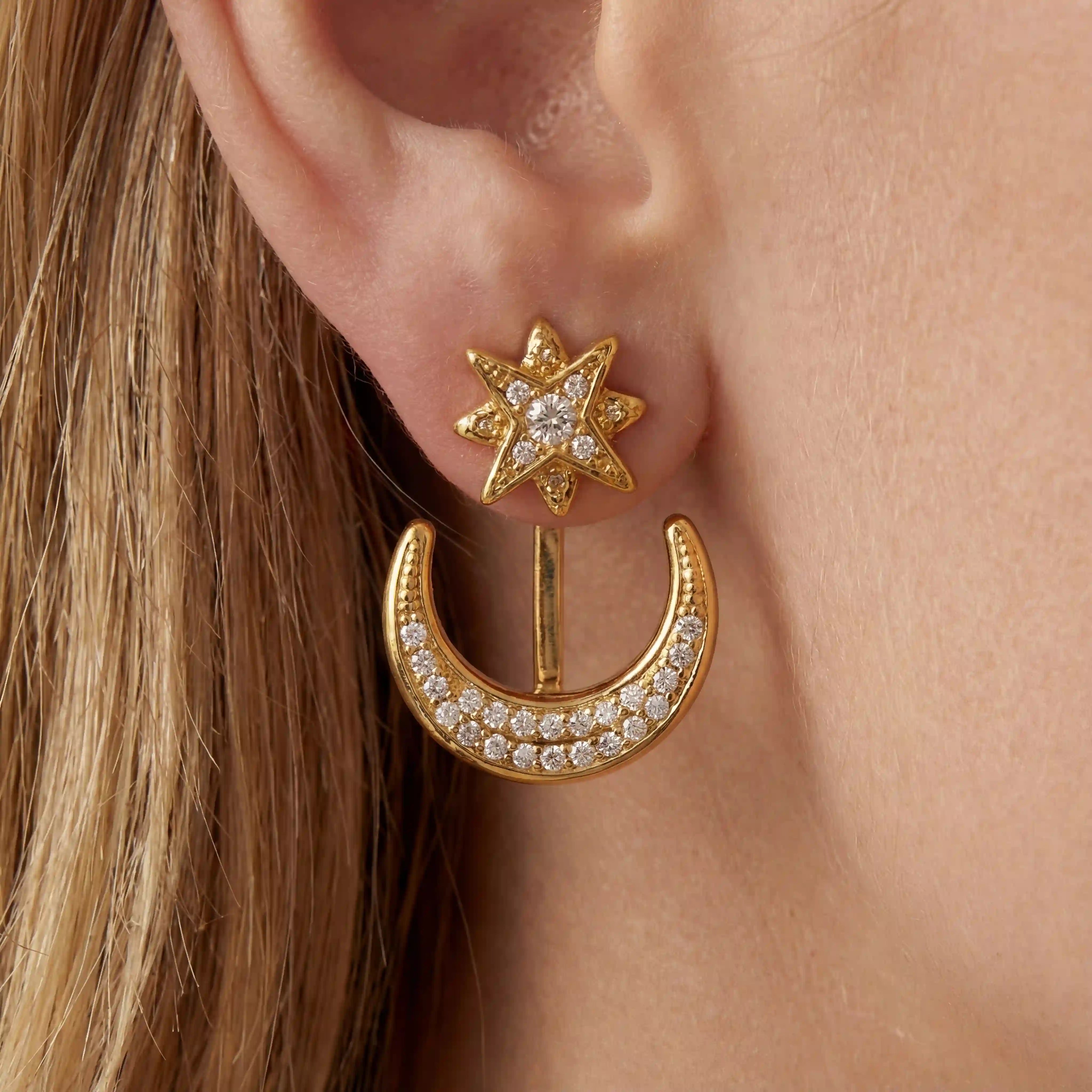 Close up of blonde woman wearing gold star and moon ear jackets celestial jewelry. Main image