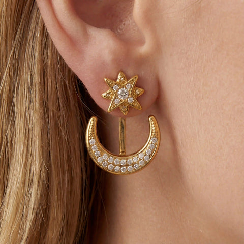 Close up of blonde woman wearing gold star and moon ear jackets celestial jewelry.