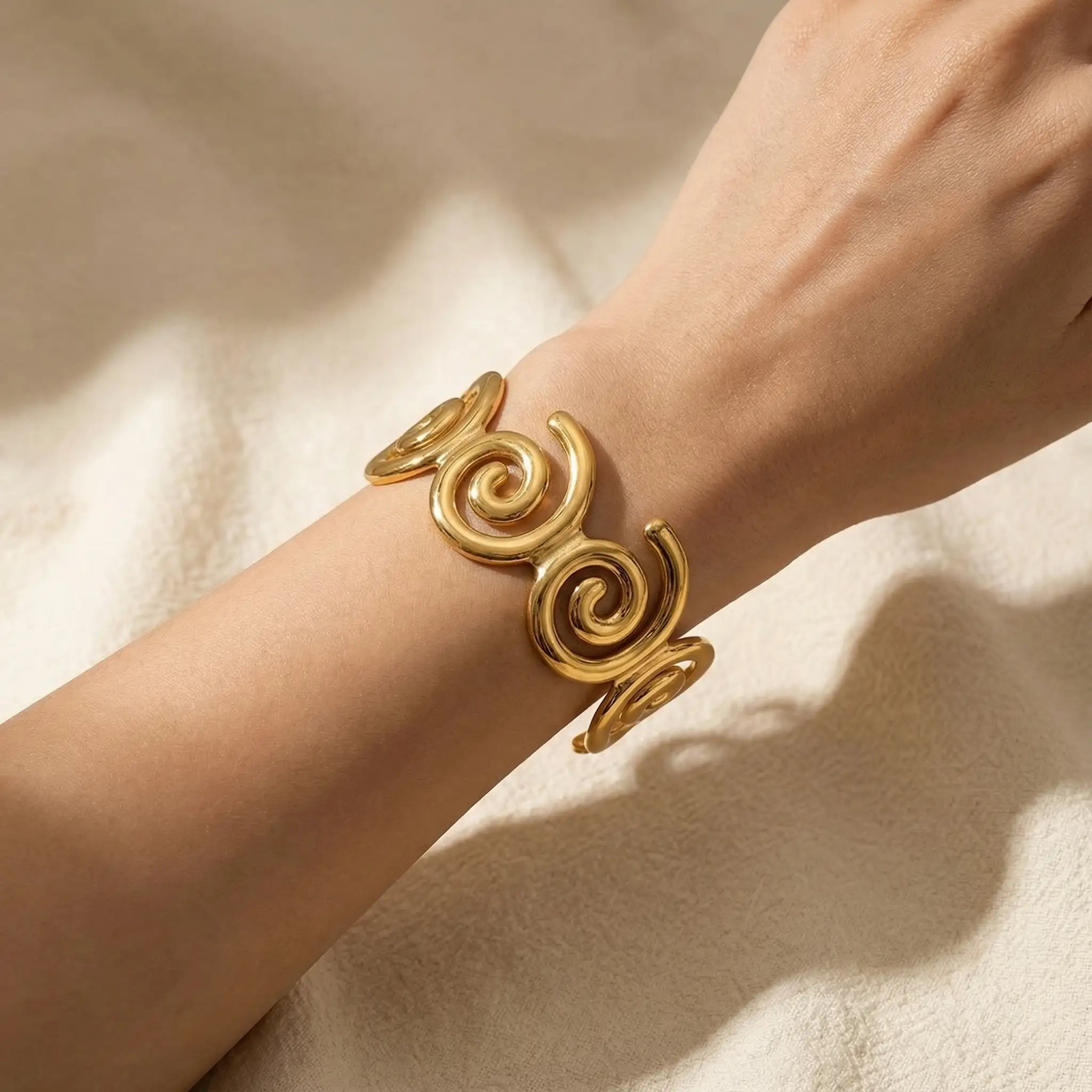 Woman wearing gold spiral statement cuff in soft natural lighting.