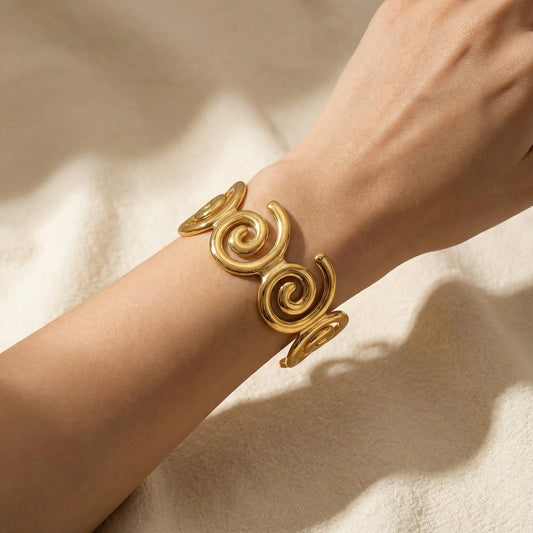 Woman wearing gold spiral statement cuff in soft natural lighting.