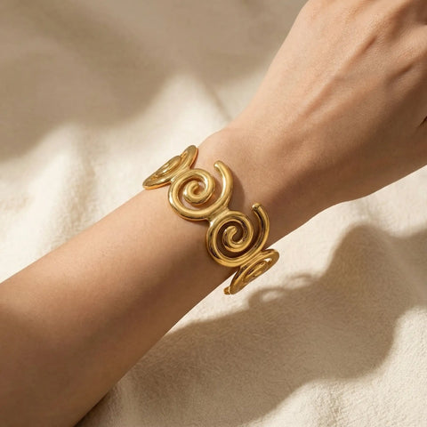 Woman wearing gold spiral statement cuff in soft natural lighting.
