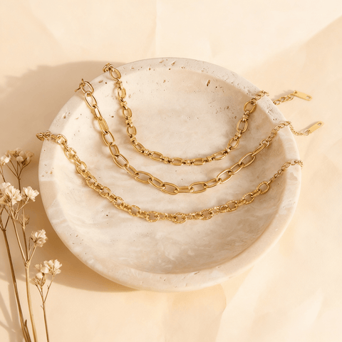 The versatile gold bracelets of The Amalfi Layering Set styled artfully inside a round, white marble dish to showcase their luxurious quality.