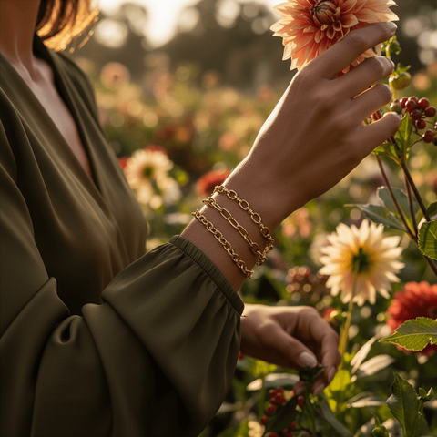 Model in an olive green top wearing The Amalfi bracelet stack in a moody, artistic shot among flowers, showcasing the jewelry's versatility.