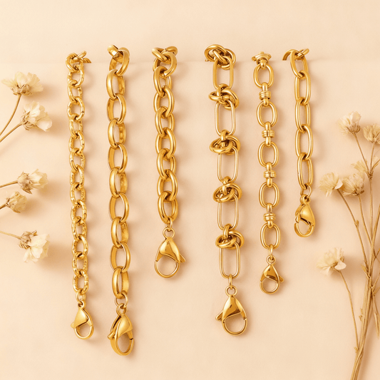 The Amalfi Layering Set by Luminova: all six waterproof gold chain bracelets laid out vertically, showcasing each unique style on a soft beige background with dried flowers.