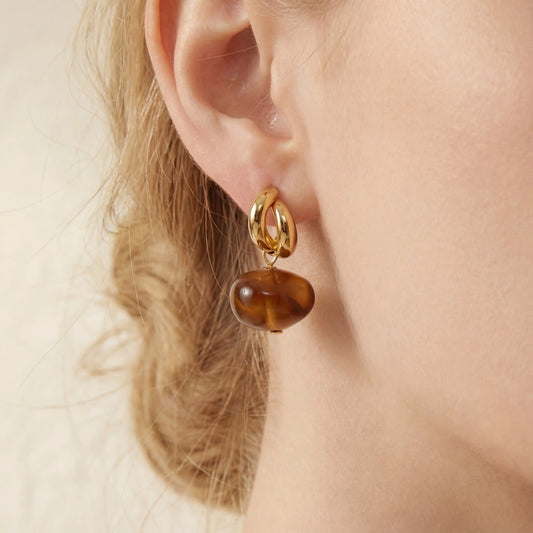 Close up detail of amber resin drop earrings on blonde model vintage style jewelry.