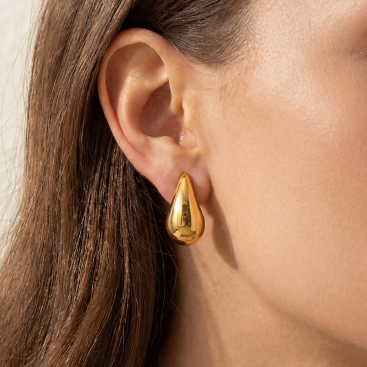 Close up of woman wearing gold Ambrosia teardrop stud earrings liquid metal design.