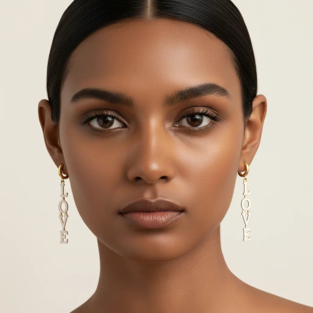 A stunning model with a deeper skin tone wearing The Amor Earrings, showcasing the beautiful contrast between the crisp white enamel, gold, and her complexion.