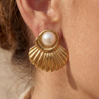 Close up of woman wearing Aphrodite gold scallop shell earrings with pearl center beach style.