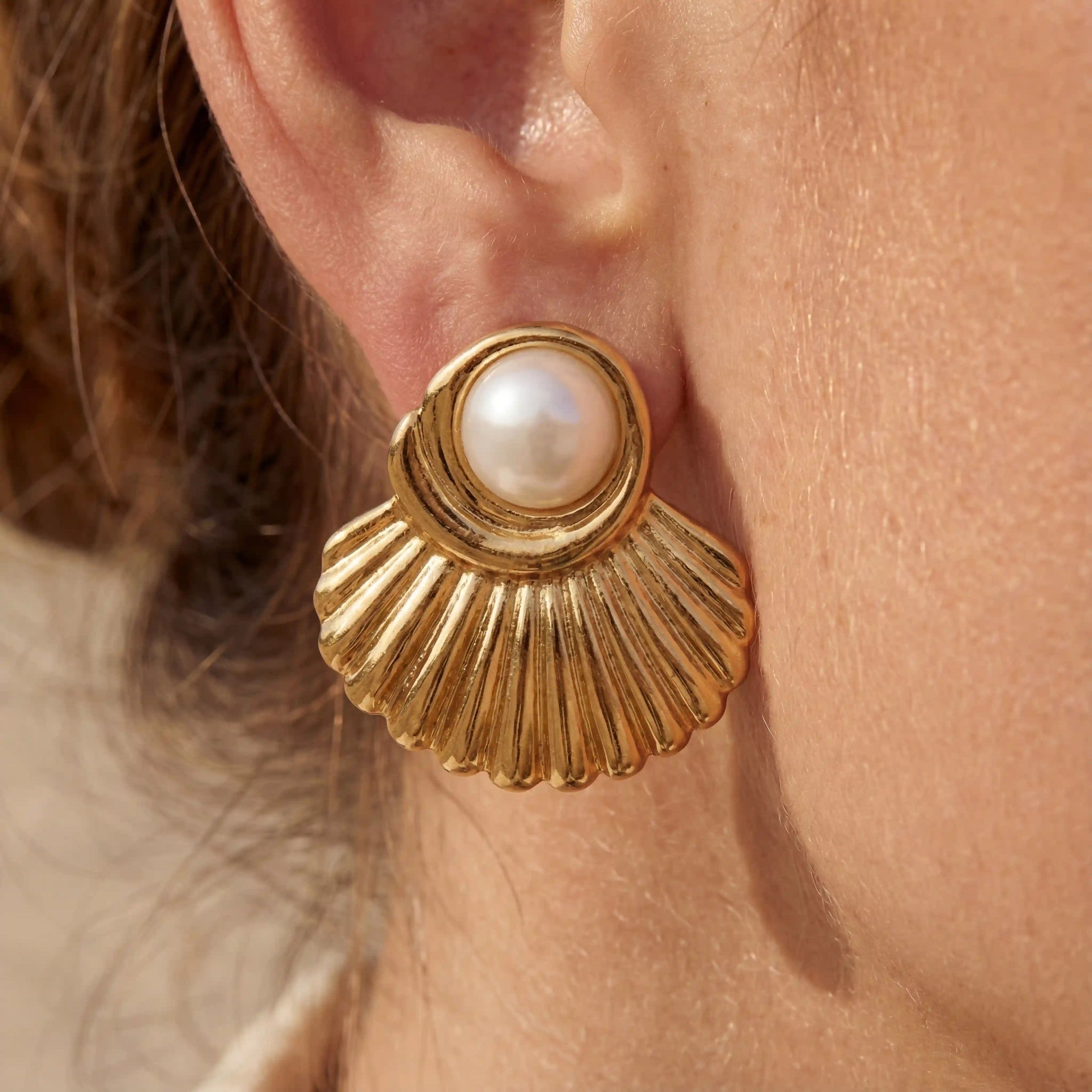 Close up of woman wearing Aphrodite gold scallop shell earrings with pearl center beach style.
