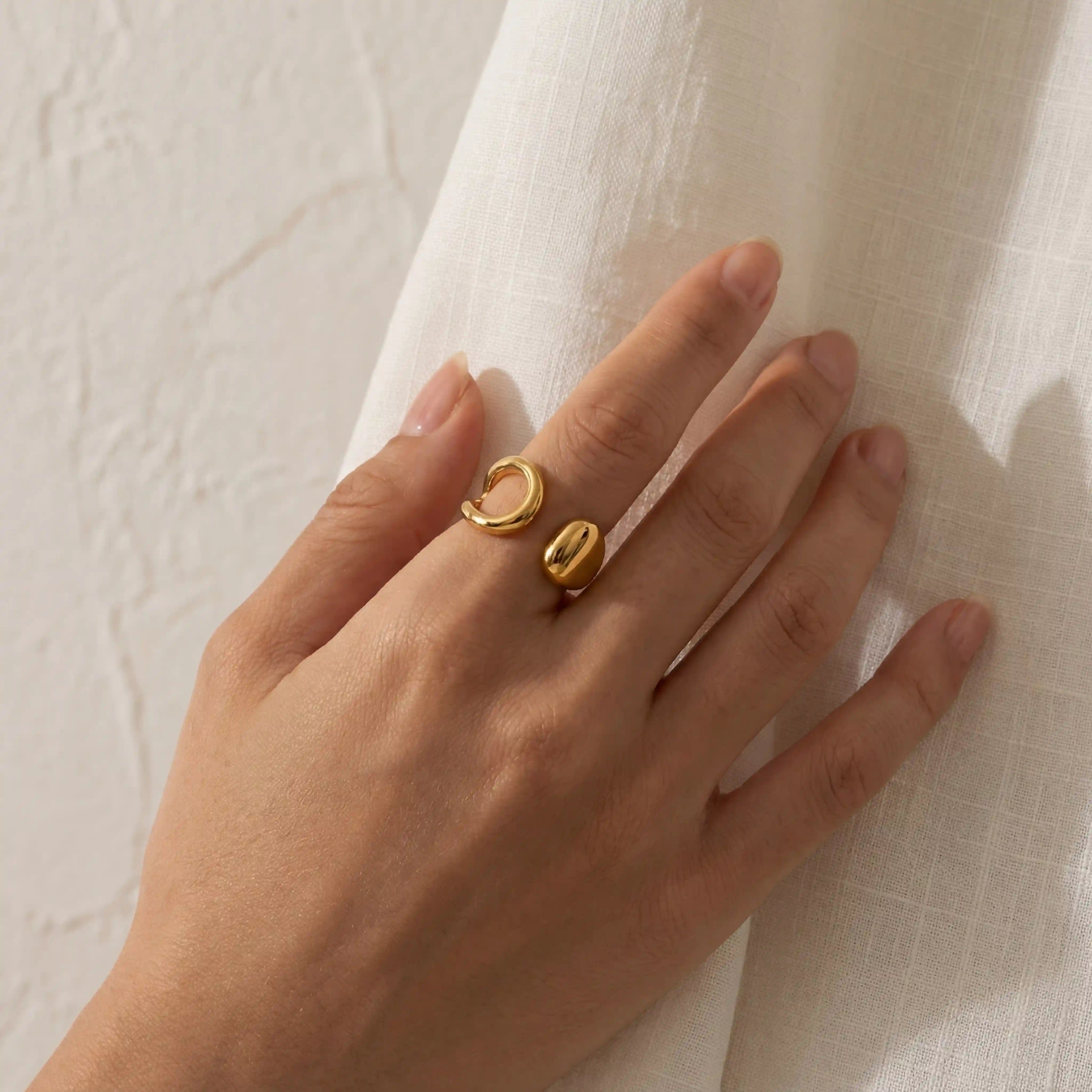 Minimalist style woman wearing gold asymmetrical ring on index finger. Main image