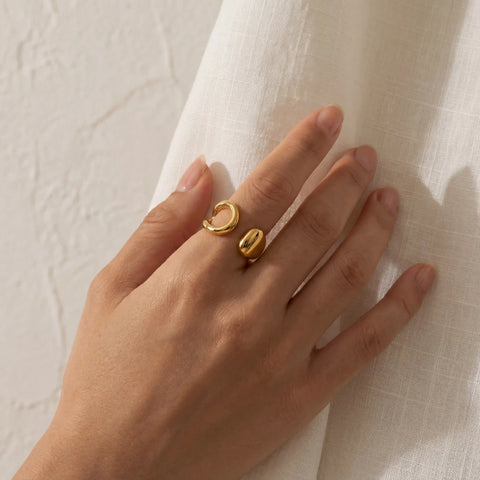 Minimalist style woman wearing gold asymmetrical ring on index finger.