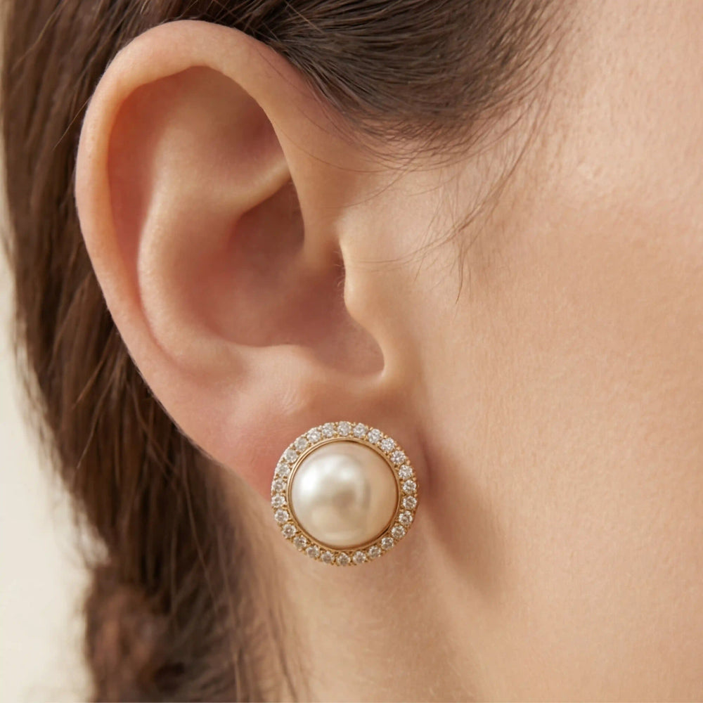 Close up of woman wearing classic pearl stud earrings with crystal halo rim Athena style.