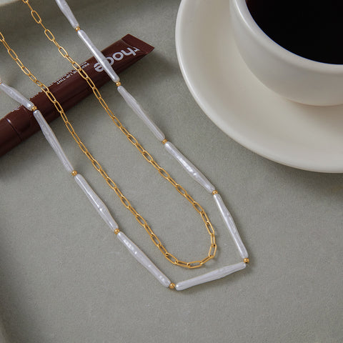 The Callisto layered necklace displayed next to a cup of coffee, embodying the effortless elegance of an everyday, on-the-go style.
