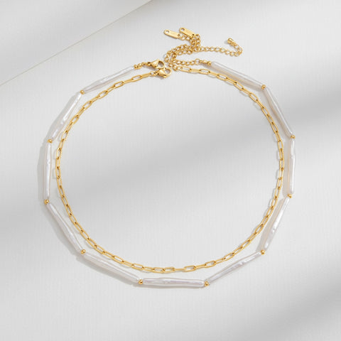 A detailed studio shot of The Callisto Necklace by Luminova, showcasing its pre-layered design with a freshwater stick pearl strand and a gold paperclip chain.