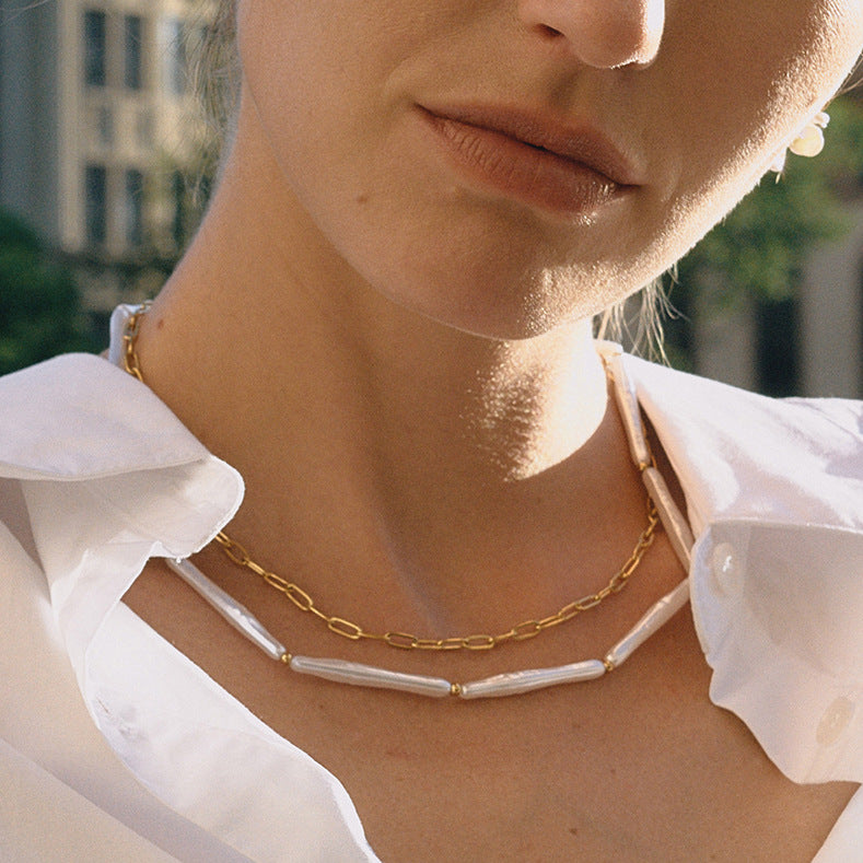 A beautiful close-up of a model wearing The Callisto Necklace with a classic white shirt, highlighting the perfect spacing and harmony of the two layers.
