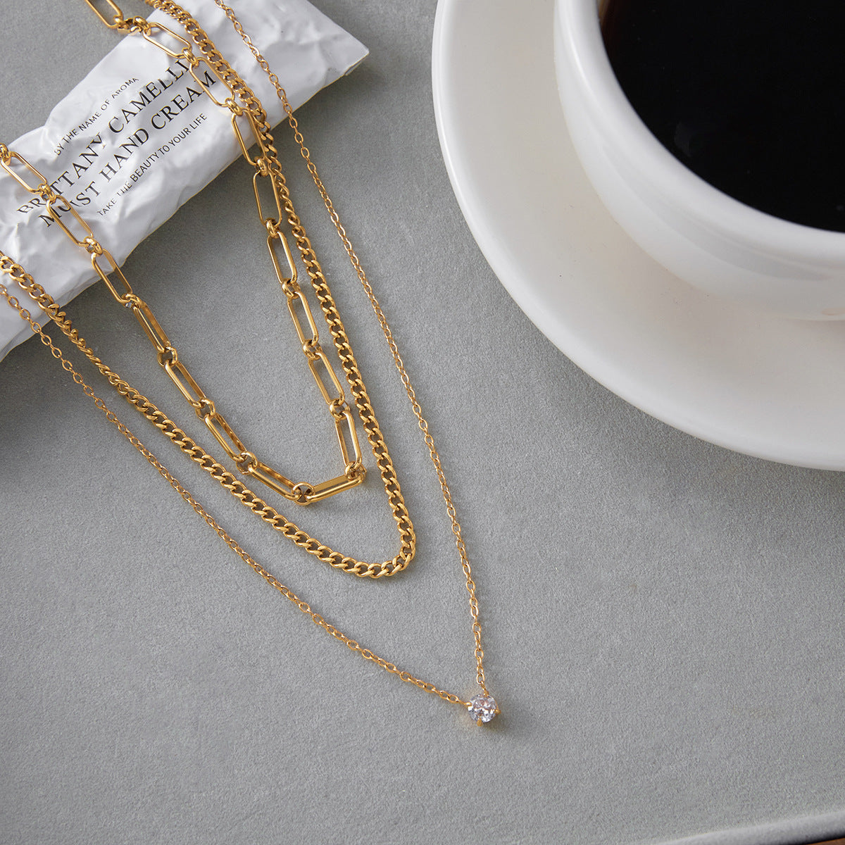 The Charites layered necklace displayed next to a cup of coffee, embodying effortless, everyday chic and sophistication.