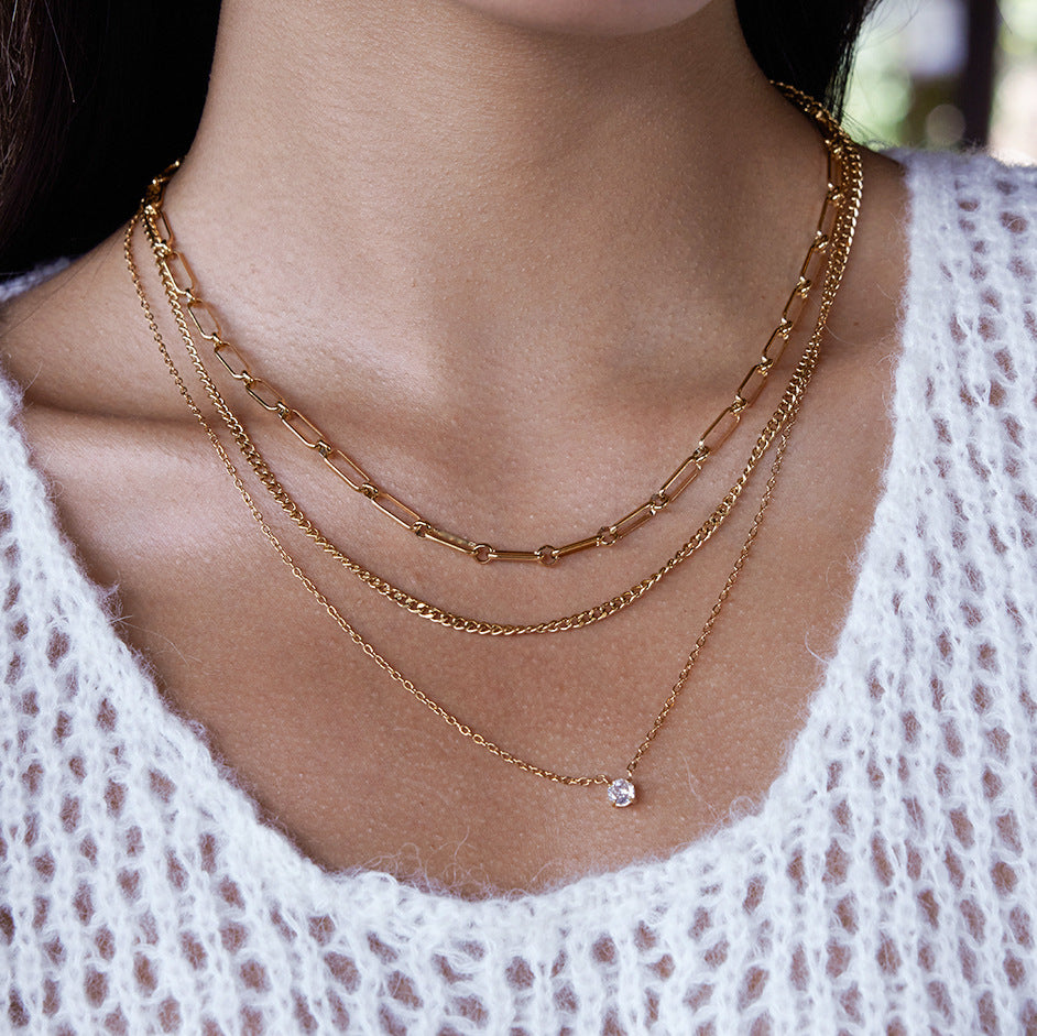 A model wearing The Charites Necklace, demonstrating how the triple-strand design elegantly fills the neckline of a simple top.