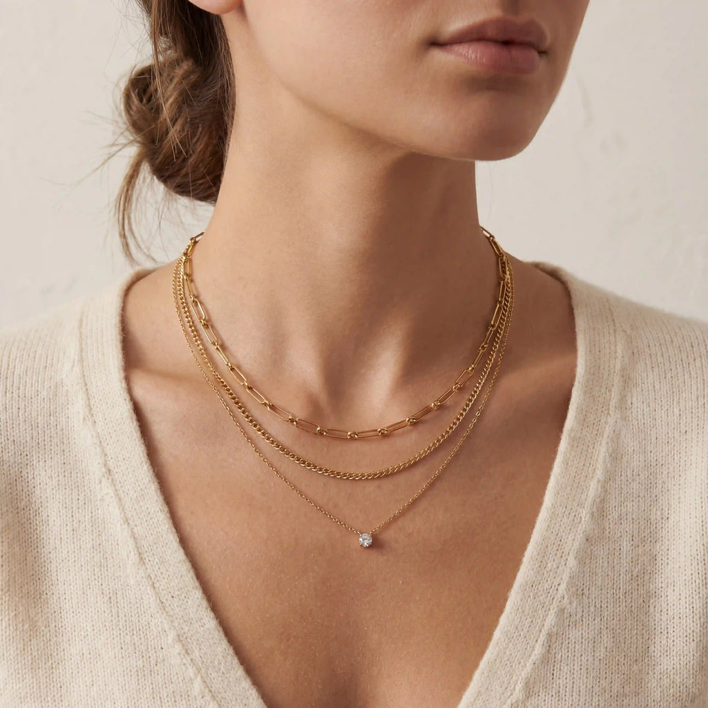An elegant shot of a model wearing The Charites Necklace, showing how the three gold strands create a full and perfectly spaced necklace stack.