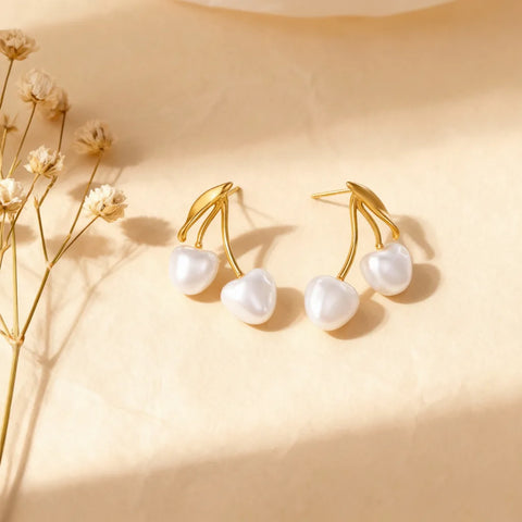 An artistic top-down shot of The Chérie Pearl Earrings casting a gentle shadow, highlighting the polished 18k gold-plated stems and lustrous pearls