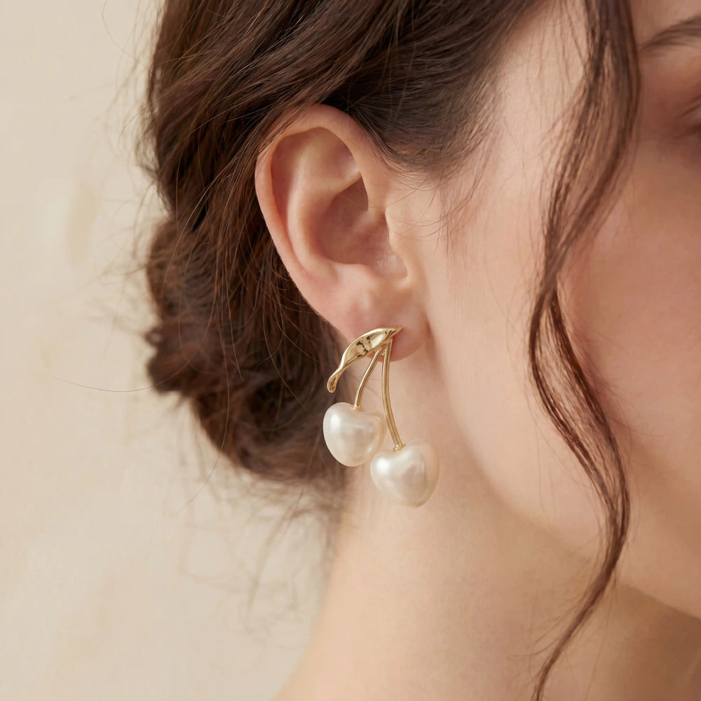 Close up of woman wearing gold and pearl cherry earrings coquette aesthetic jewelry.