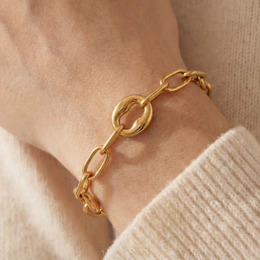 Close up of woman wearing chunky gold link bracelet with alternating organic oval links.