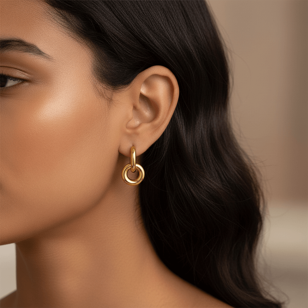 Close-up side profile of a woman wearing Luminova gold knot hoops, showcasing how they dangle from the ear.