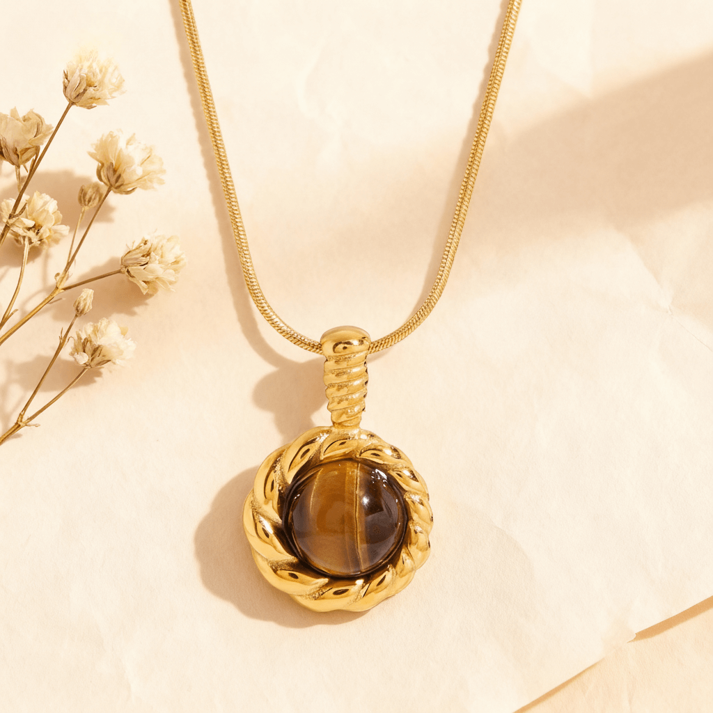 The Courage Stone Necklace featuring a polished, rectangular Tiger's Eye pendant with golden-brown bands, hanging on a sleek titanium steel chain against a neutral background.