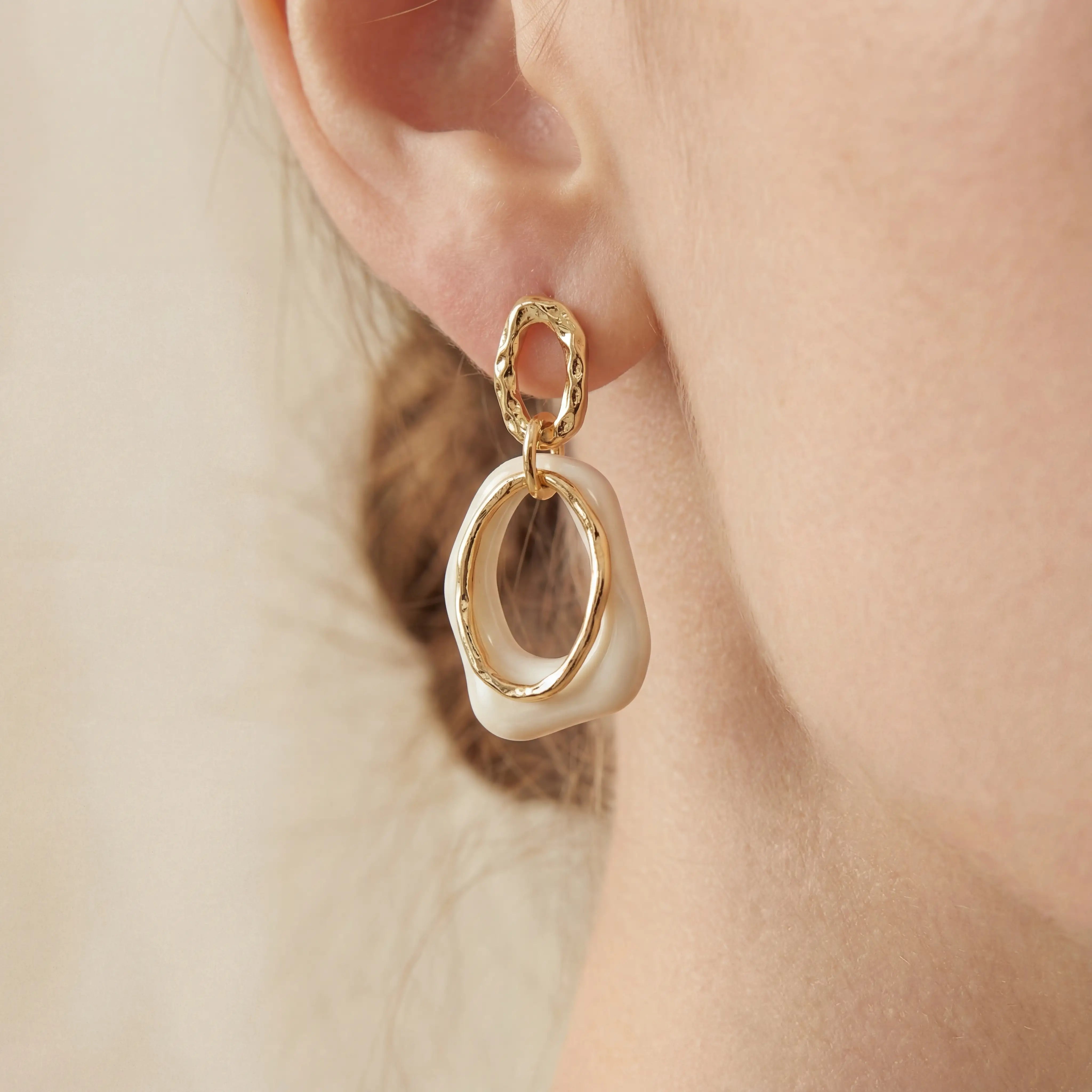 Close up of woman wearing vintage style cream and gold link earrings. Main image