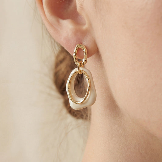 Close up of woman wearing vintage style cream and gold link earrings.
