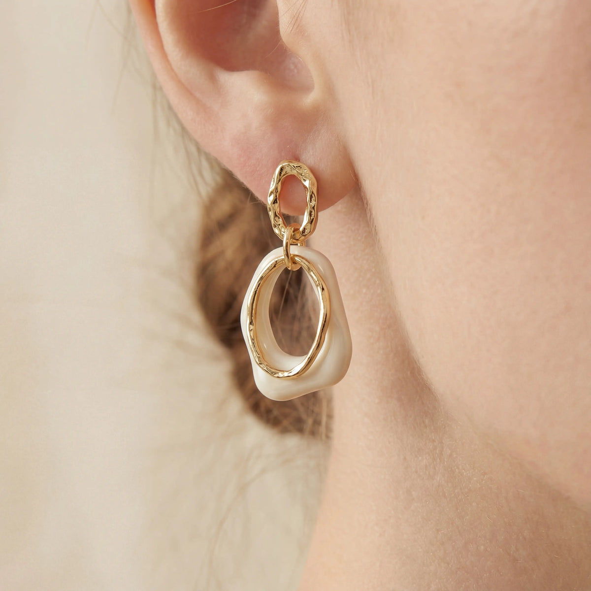 Close up of woman wearing vintage style cream and gold link earrings.
