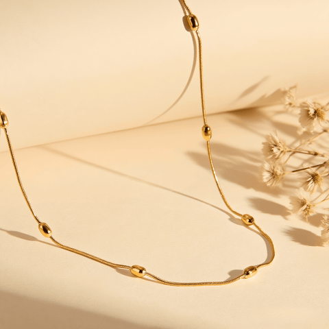 Extreme close-up macro shot of the delicate gold beads on the chain, highlighting texture and craftsmanship.